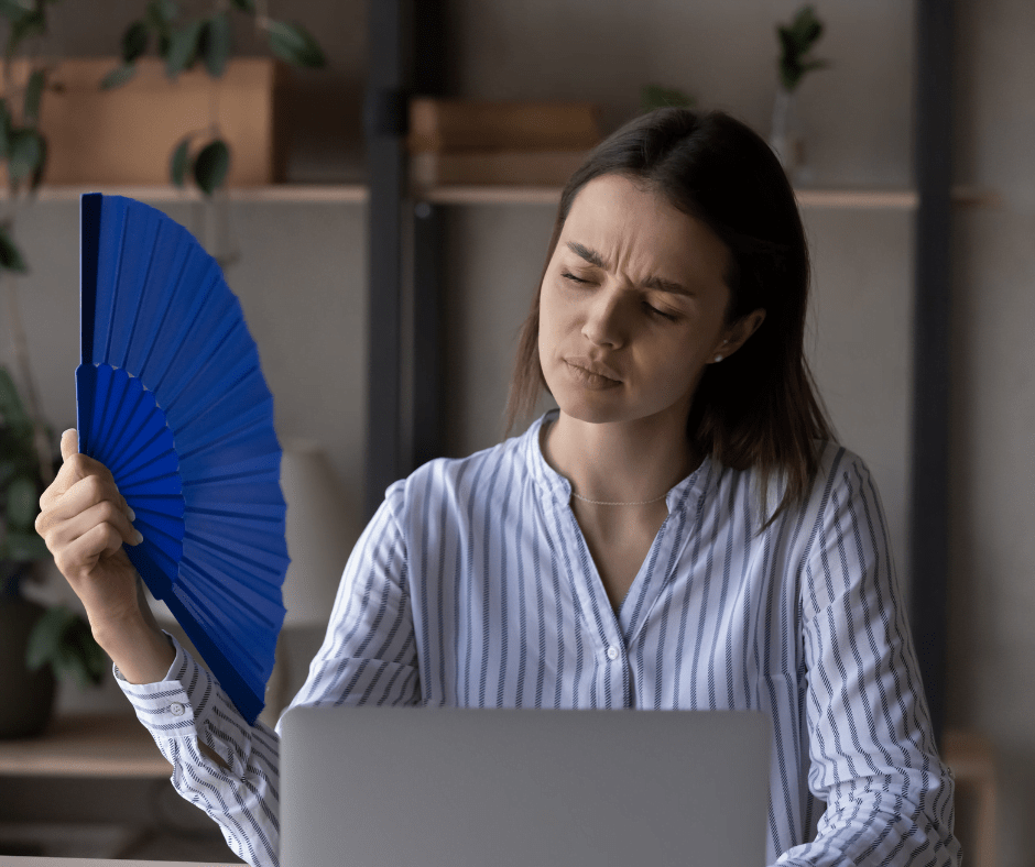 a person fanning themselves because of stuffy indoor air