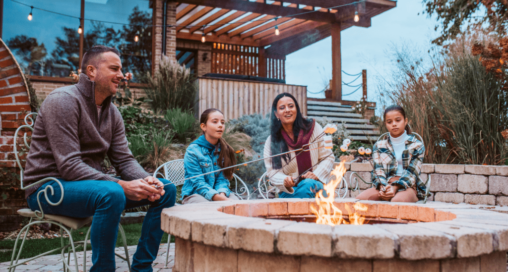 A Family Roasting Marshmallows on a Multi-Functional Backyard Fire Pit.